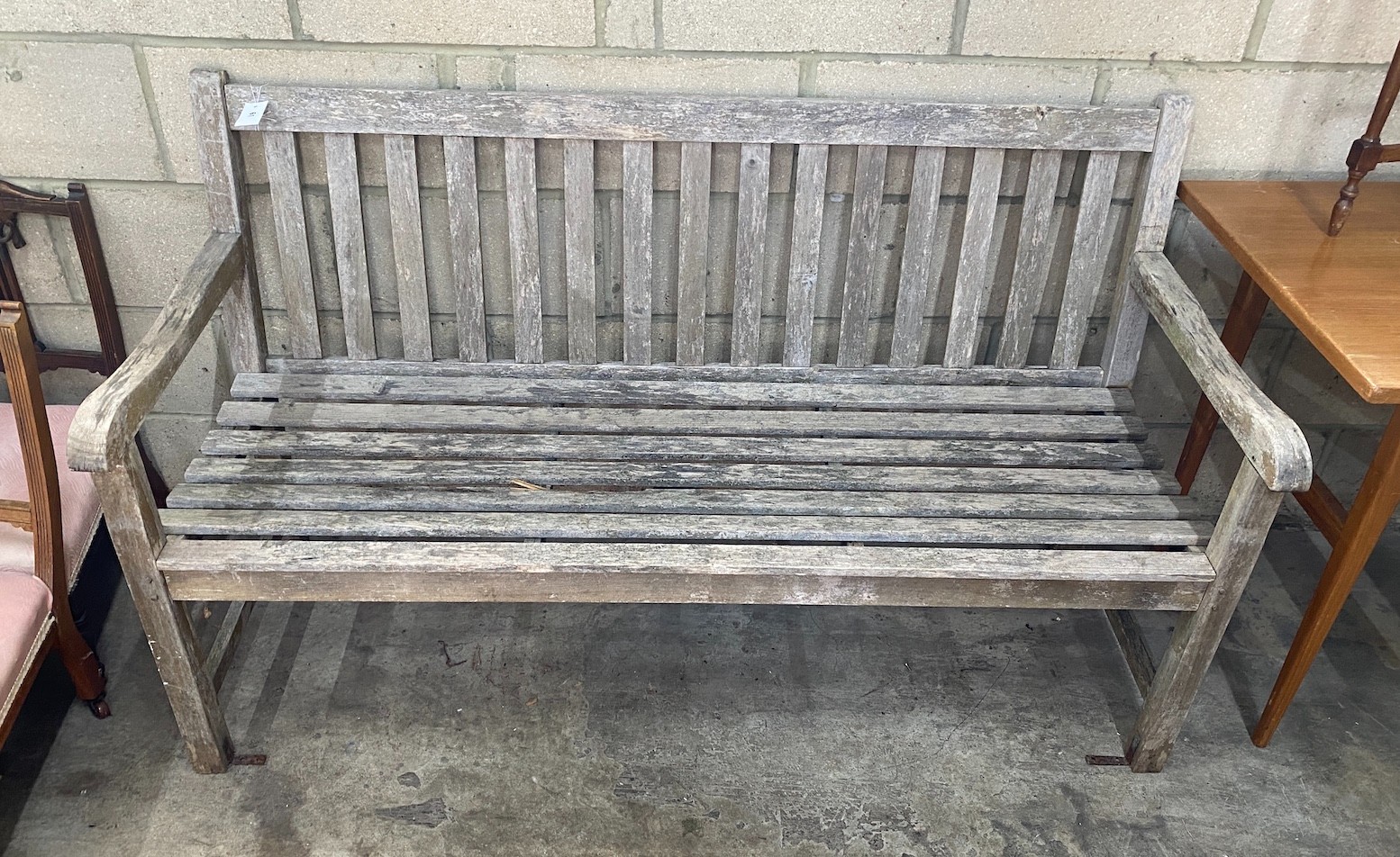 A weathered teak garden bench, length 153cm, depth 59cm, height 89cm
